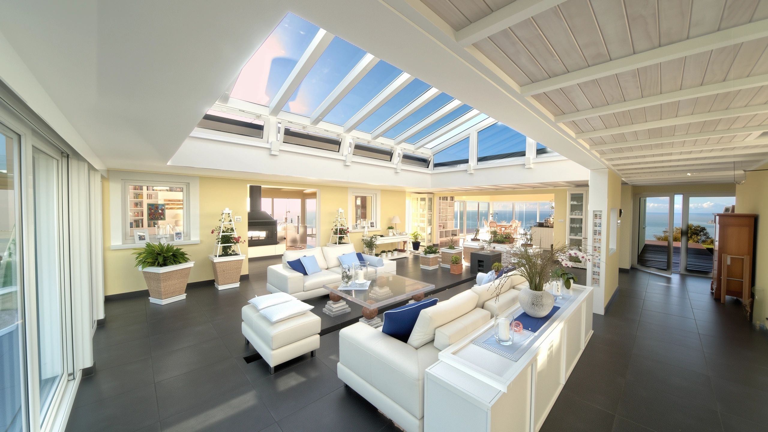 Open concept living room view across Atrium sofas towards kitchen, dining area, and distant ocean views in luxury home.