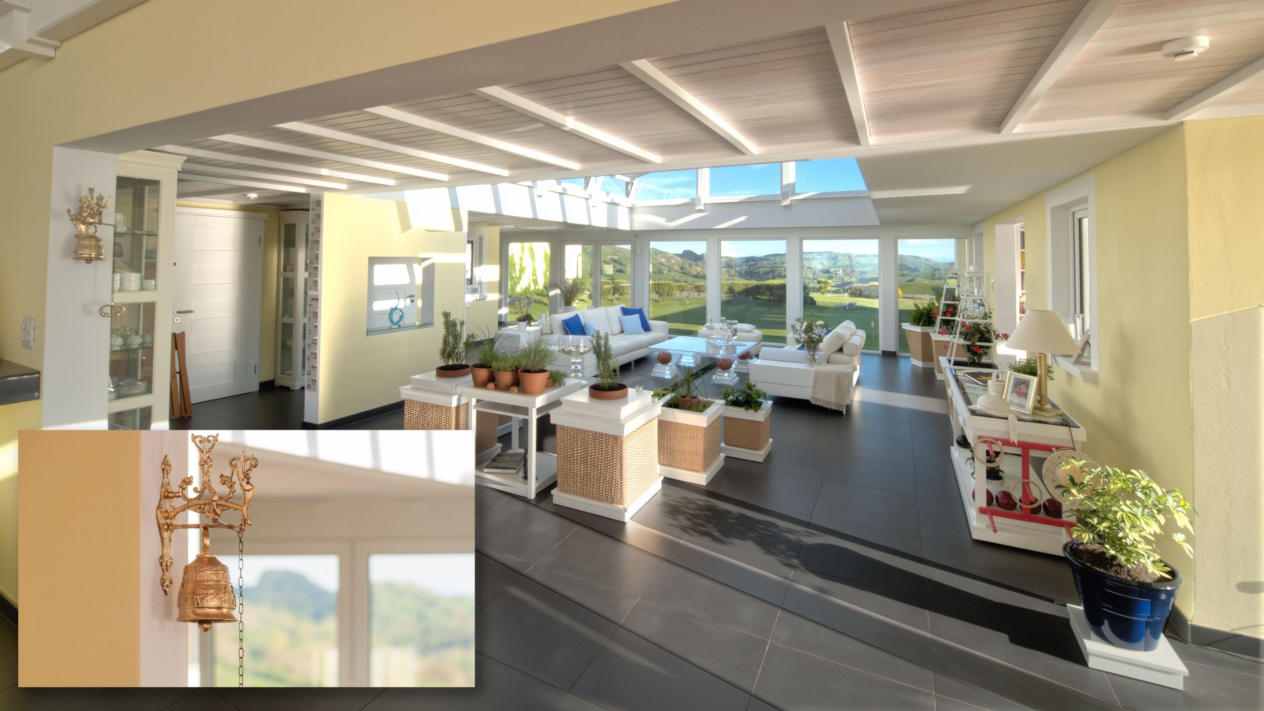 Bright four season sunroom atrium in beautiful big house with white sofas, plants, and decorative brass bell.