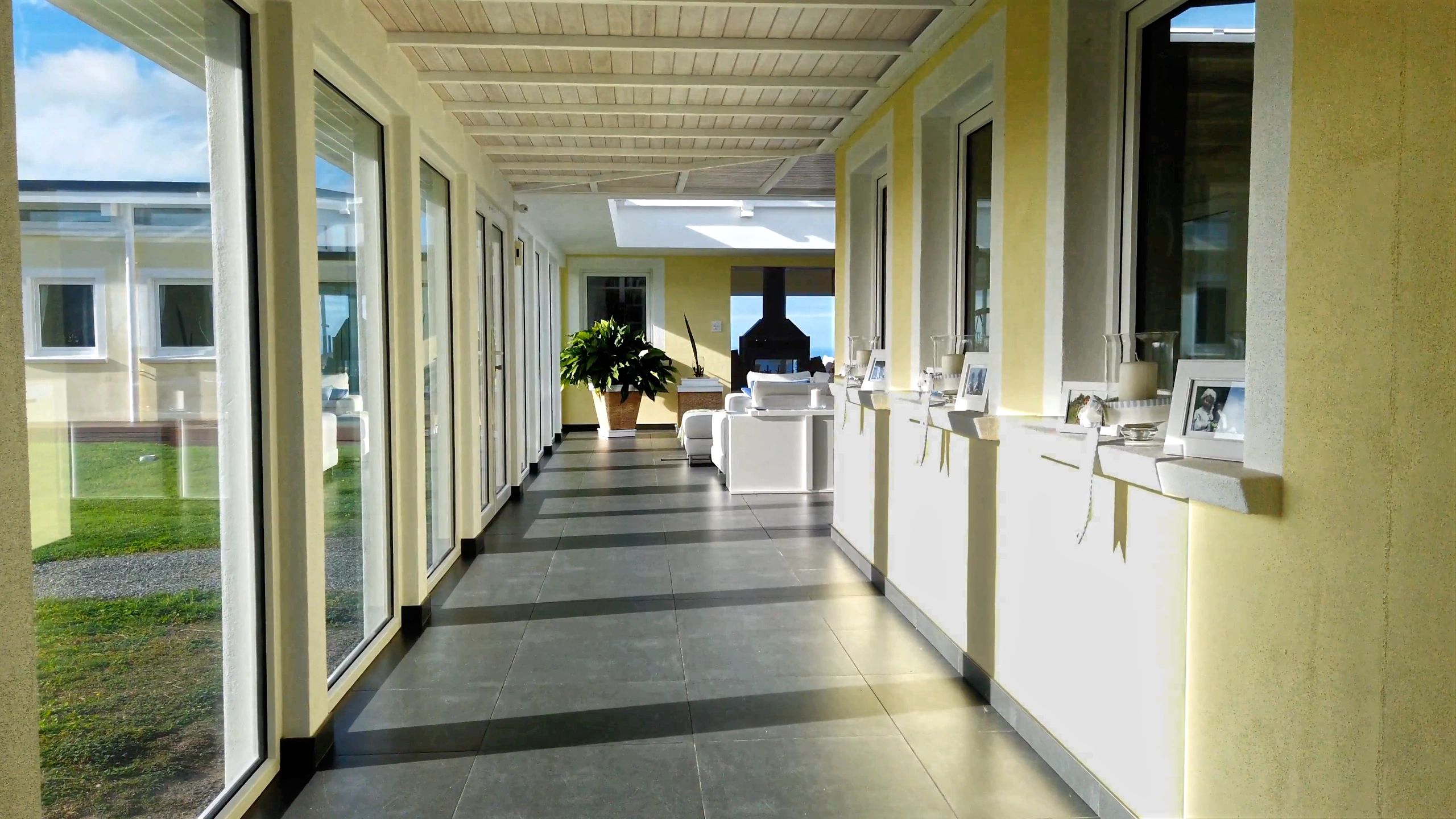 Wide walkway in open concept living area with tiled floor, internal windows, sills, and exterior views.