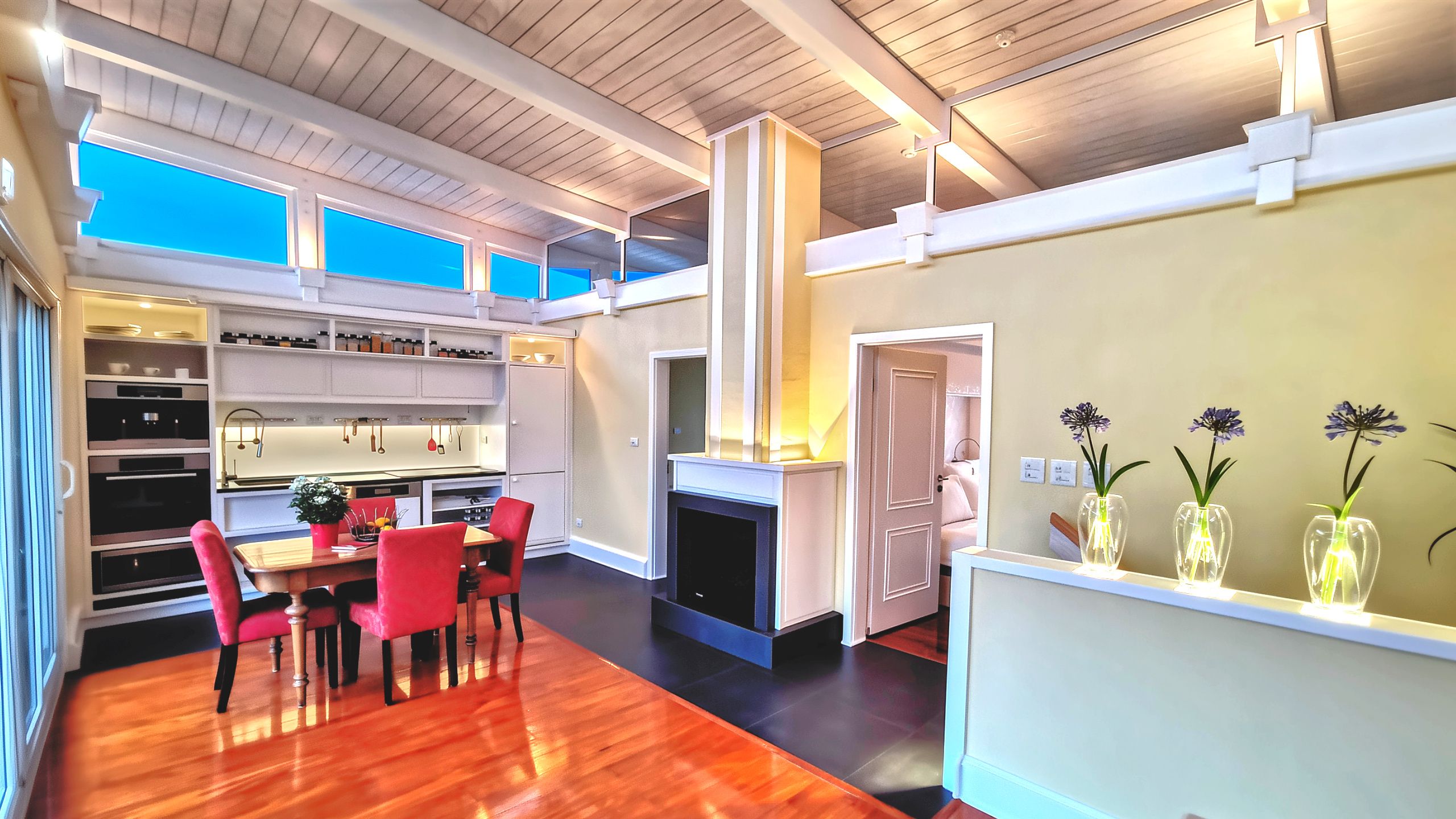 Open concept kitchen, dining, and living area in self-contained guest house unit with fireplace and balcony access.
