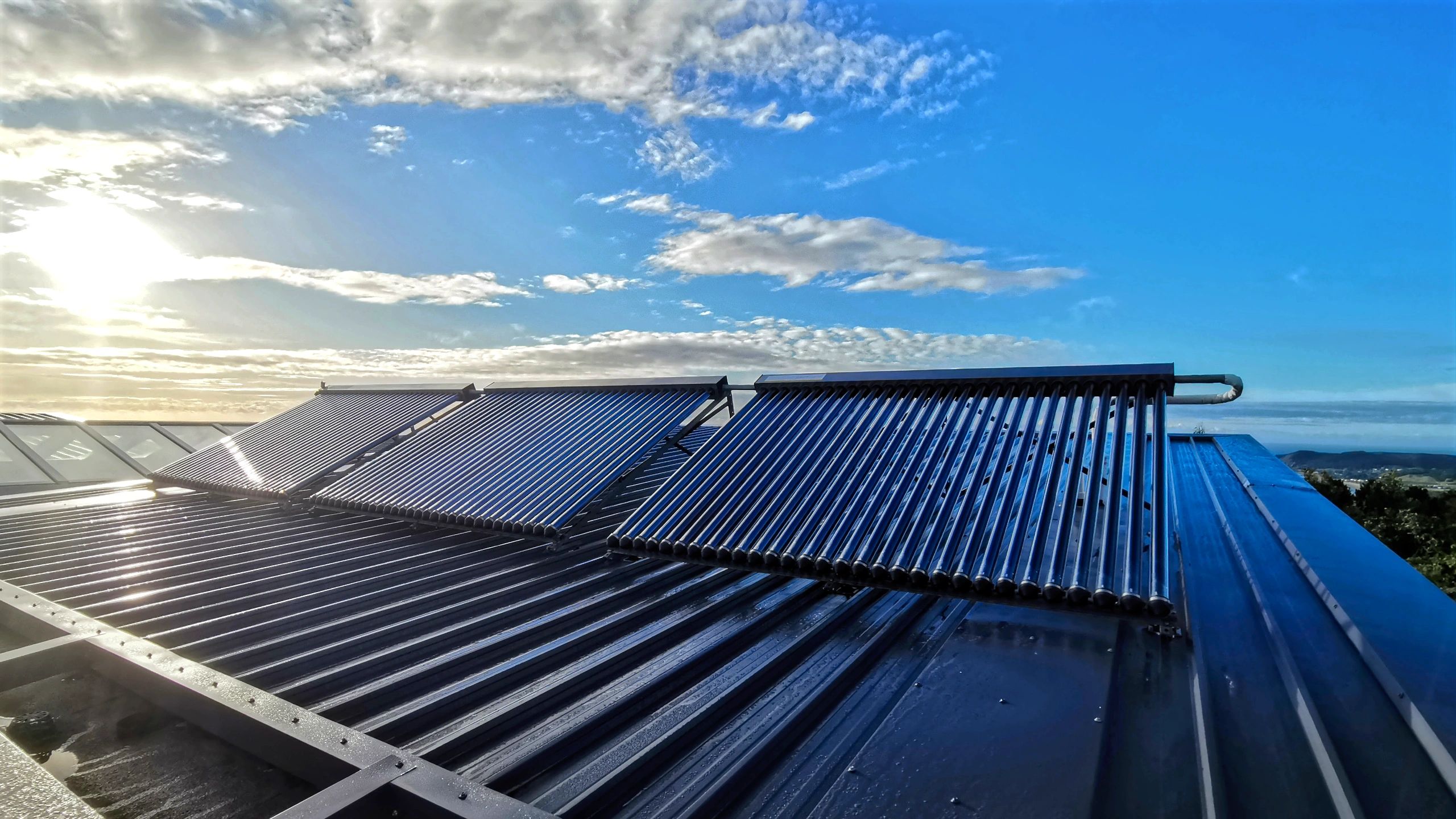 Solar energy collector tubes on roof of eco-friendly beachside house for sustainable hot water heating.