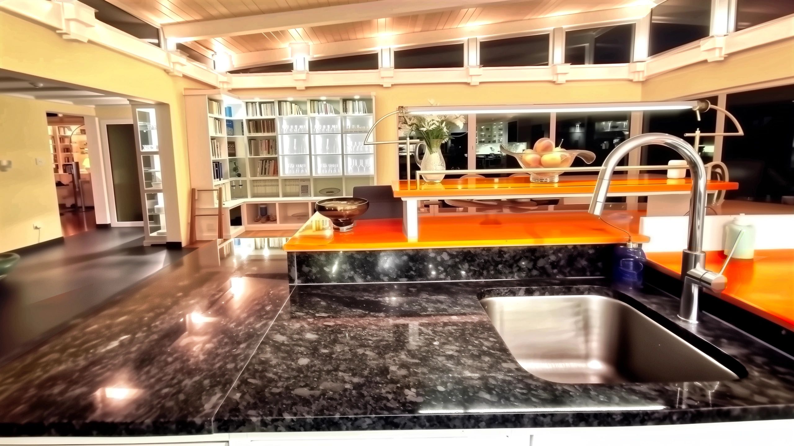 Modern kitchen design sink area overlooking bookcase and dining space in oceanfront property for sale.