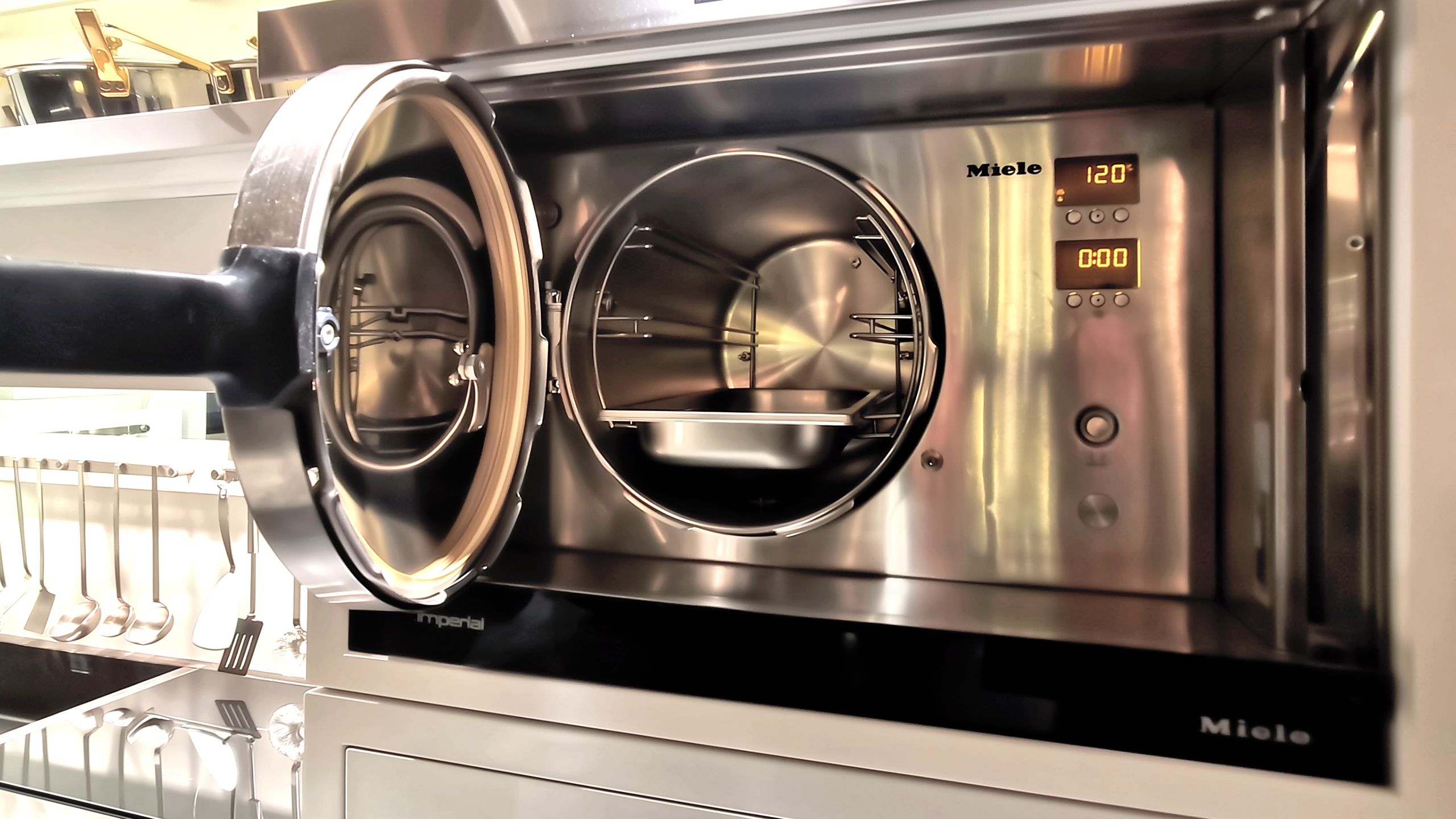 Miele pressure steam oven open, showcasing stainless steel interior in luxury villa kitchen.