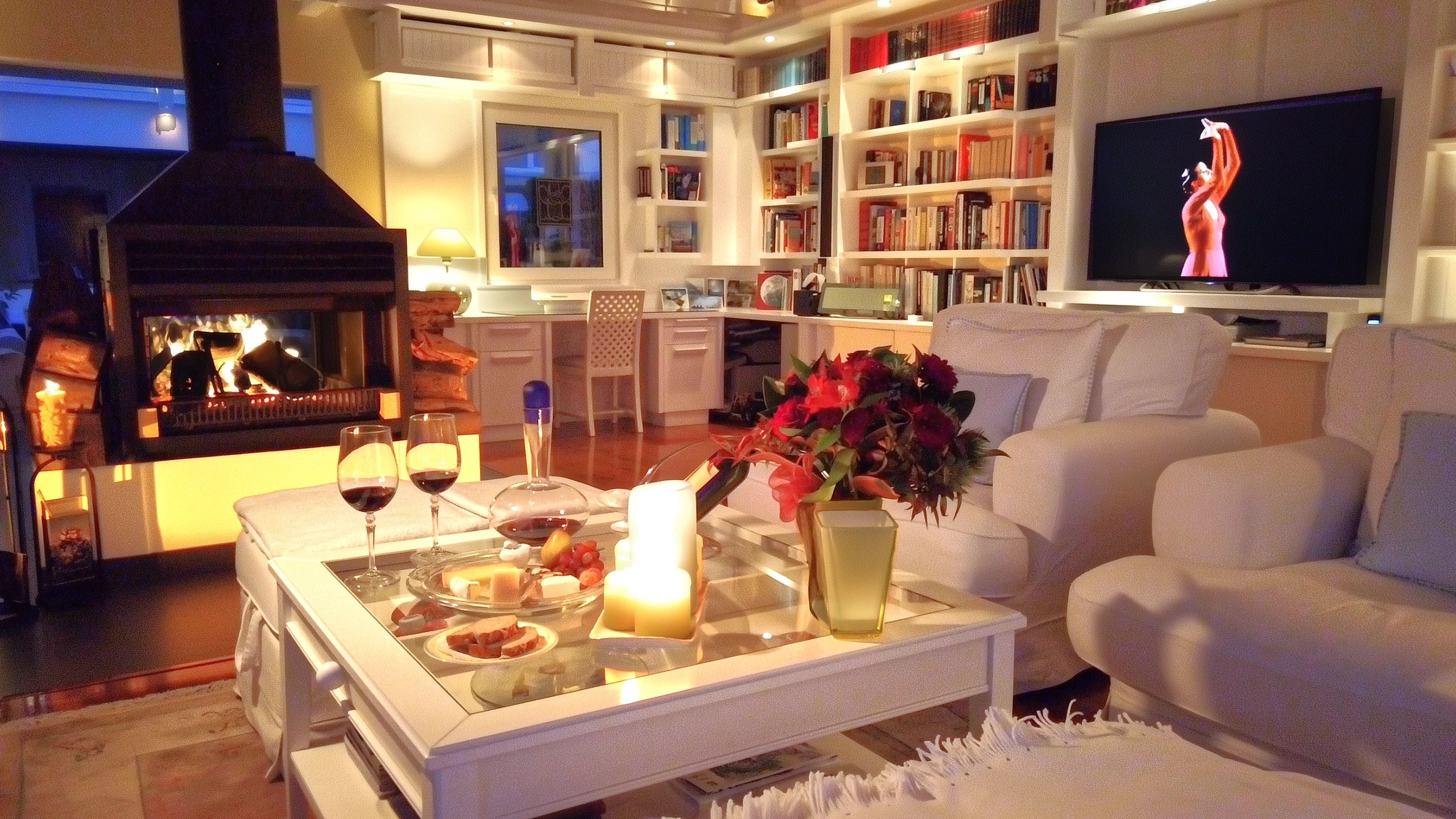 Double sided fireplace lit in cozy living room of private property NZ, set for evening relaxation with wine and cheese.
